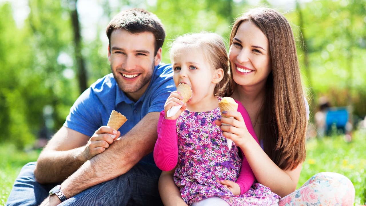 Die saisonale Familien-Checkliste: Sommer - Familie isst Eis auf Picknickdecke