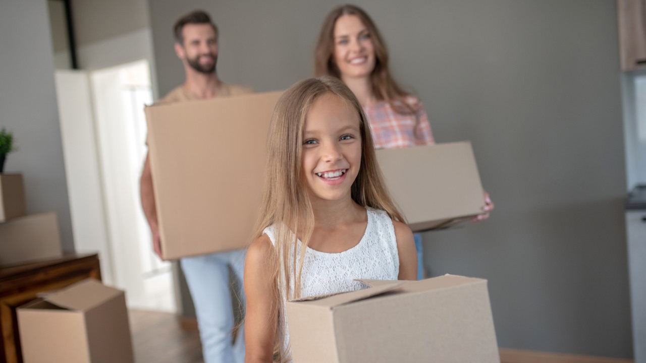 Neuanfang im Ausland - Familie trägt Umzugskarton ins Haus